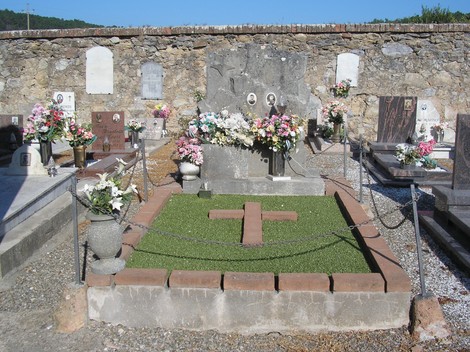 Sepolcro di Boschi e Borgianni, decorato con fiori e una croce, in un cimitero tranquillo.