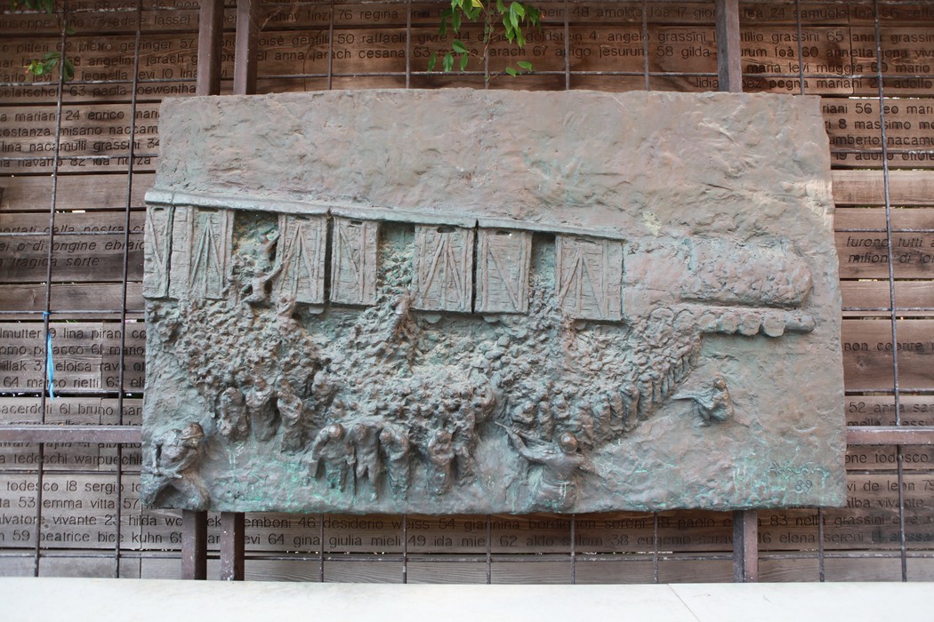 Scultura che rappresenta una folla davanti a un treno, simboleggiando l'ultimo viaggio e la memoria storica.