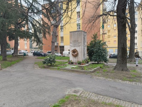 Monumento ai partigiani uccisi a San Ruffillo, circondato da vegetazione e edifici residenziali.