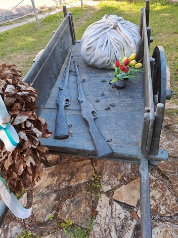 Carretto delle lavandaie con rifles, decorato con fiori e oggetti d'epoca, immerso in un contesto naturale.