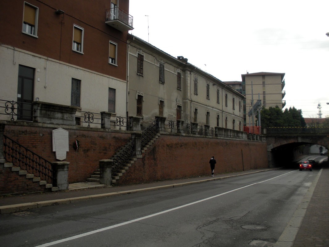 Lapide commemorativa a Quarleri, visibile su un muro di un edificio lungo una strada.