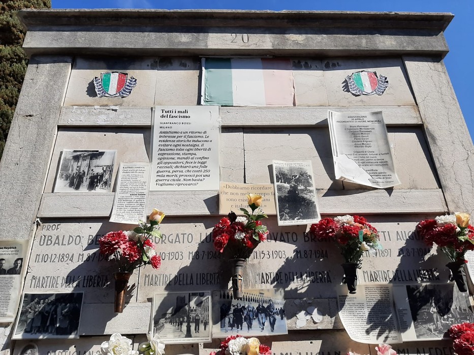 Sacrario ai martiri della libertà, con fotografie storiche e decorazioni floreali in un ambiente commemorativo.