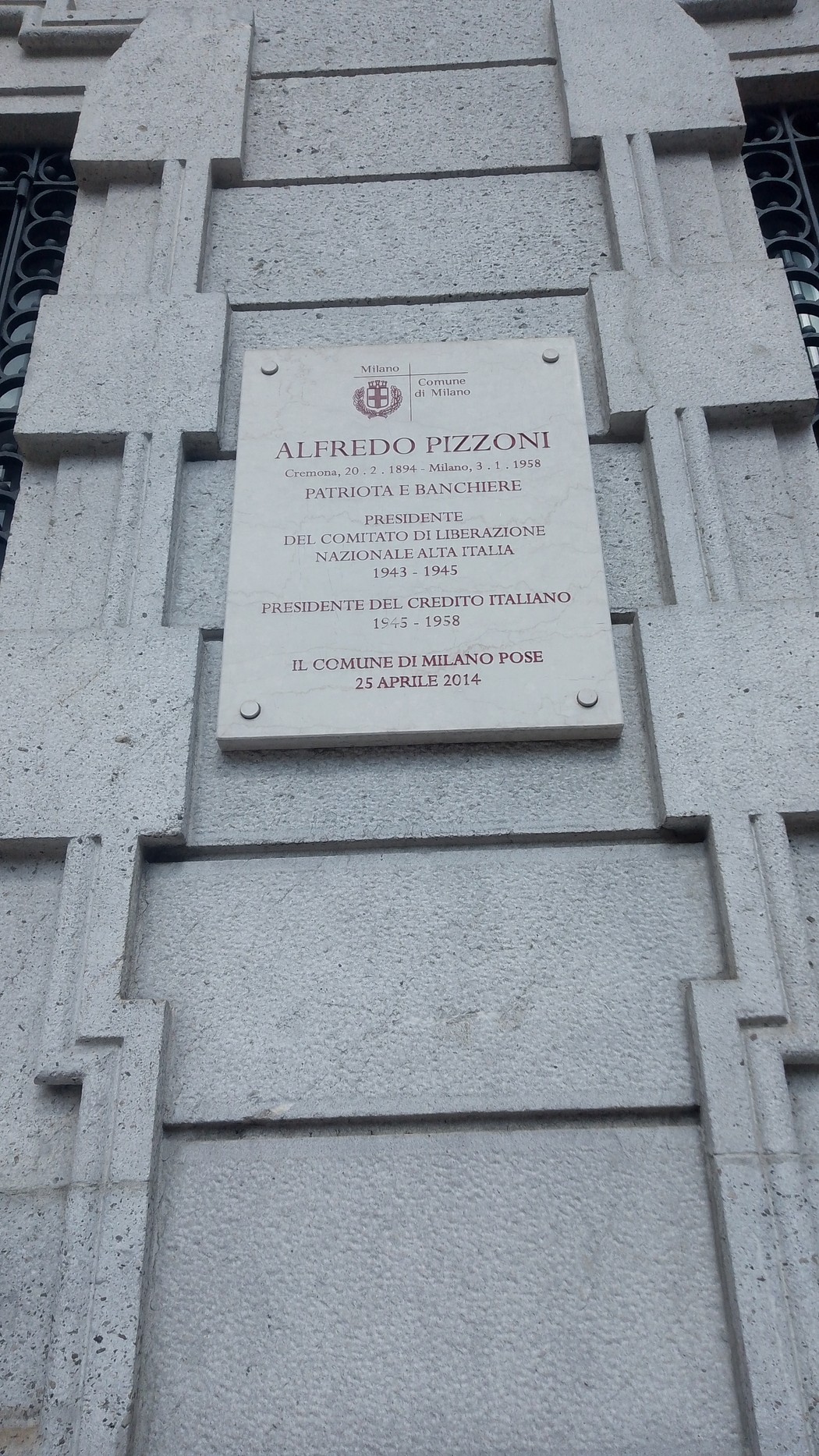 Lapide in pietra con iscrizione, fissata alla facciata di un edificio.