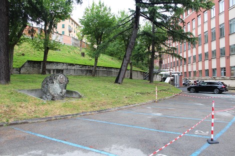 Il Monumento ai martiri della Resistenza è visibile in un'area verde con alberi, accanto a un parcheggio.