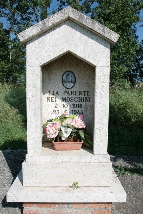 Tabernacolo di pietra dedicato a Lia Parenti, con fiori e una fotografia commemorativa.