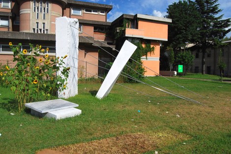 Monumento a Umile: scultura contemporanea in un giardino, con elementi architettonici e vegetazione circostante.