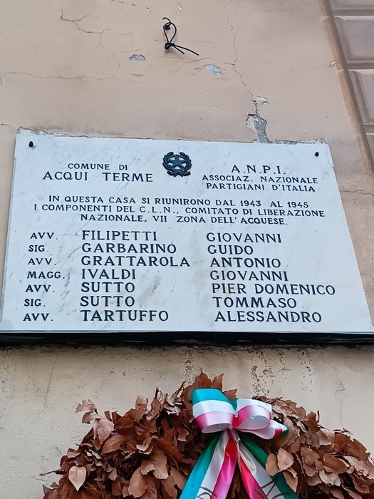 Lapide commemorativa che onora i membri del CLN acquese, con iscrizioni e nomi di partigiani.