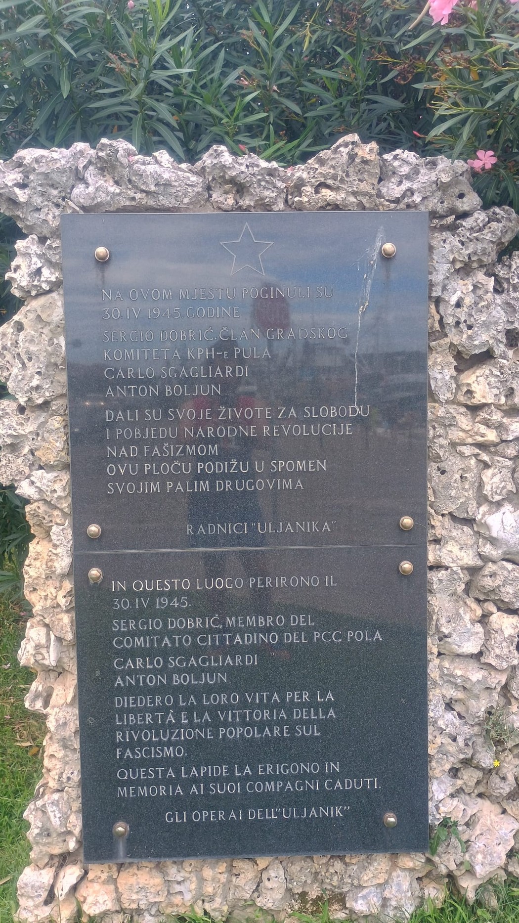 Lapide commemorativa dedicata a Dobrić, Sgagliardi e Boljun, situata in un contesto naturale.