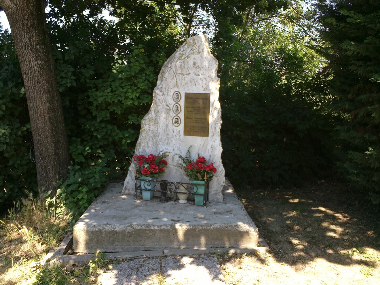 Monumento dedicato a Giovanardi, Gennari e Tarasconi, con una stele bianca e decorazioni floreali.