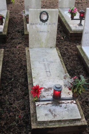 tombe di caduti per la libertà, con decorazioni floreali e candele accese, in un commemorativo cimitero.