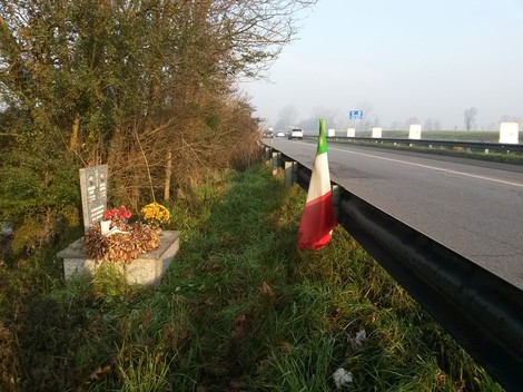Lapide commemorativa dedicata a Fagnani e Garanzini, situata lungo una strada, con fiori e bandiera italiana.