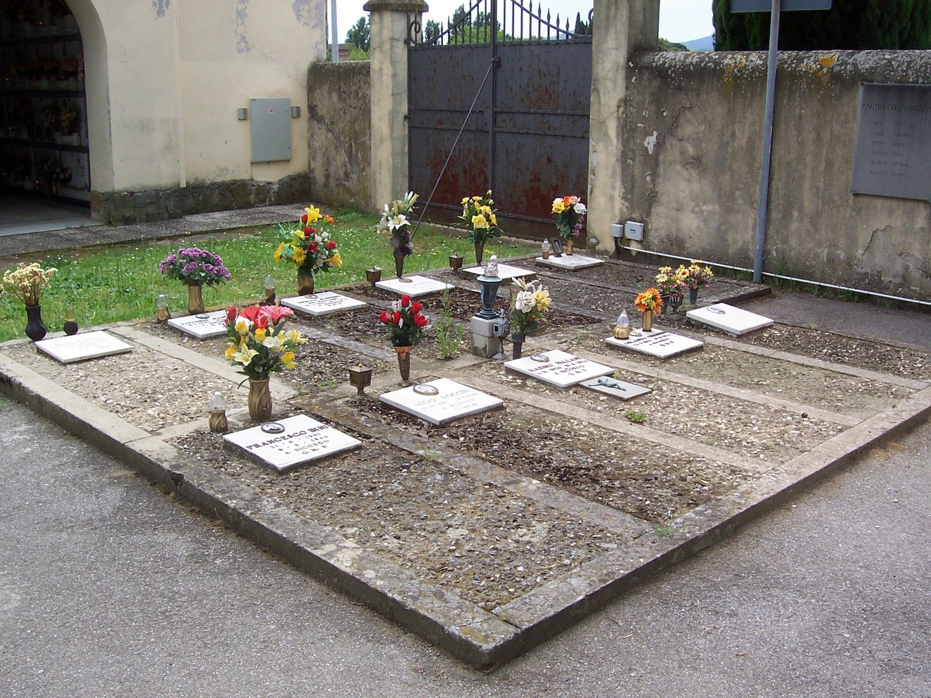 Sacrario del cimitero di Badia a Settimo, con fiori e lapidi in un’atmosfera di commemorazione e rispetto.