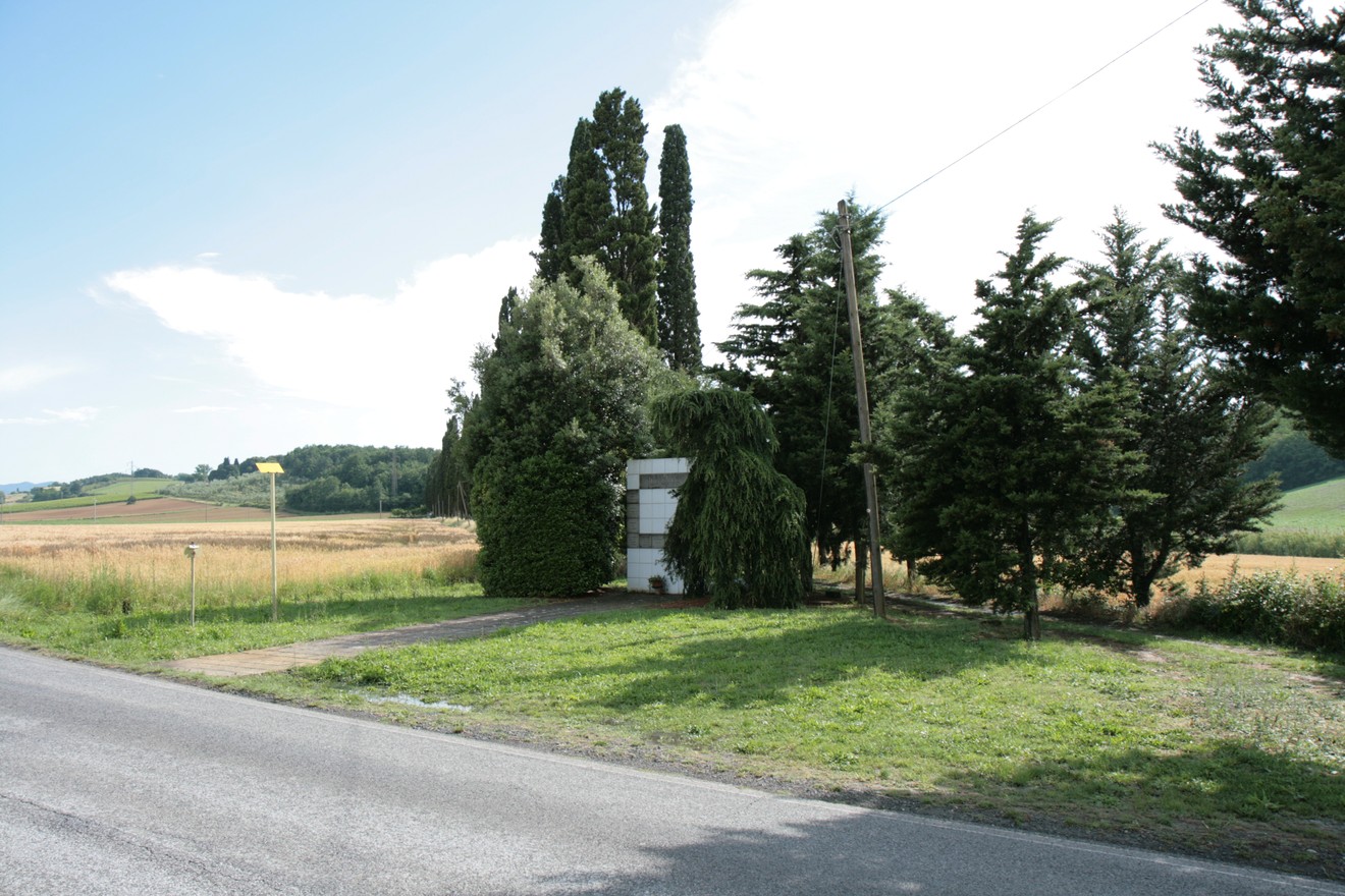 Monumento de La Rosa, situato in un paesaggio rurale, circondato da alberi e campi.