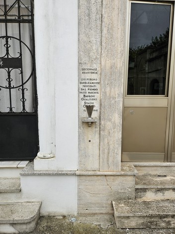 Iscrizione in pietra che indica l'accesso a Barboni e Stagni, decorata e affissa su una parete esterna.