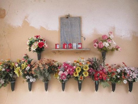 Lapide commemorativa decorata con fiori freschi e candele, in ricordo di Bonino e Coda.