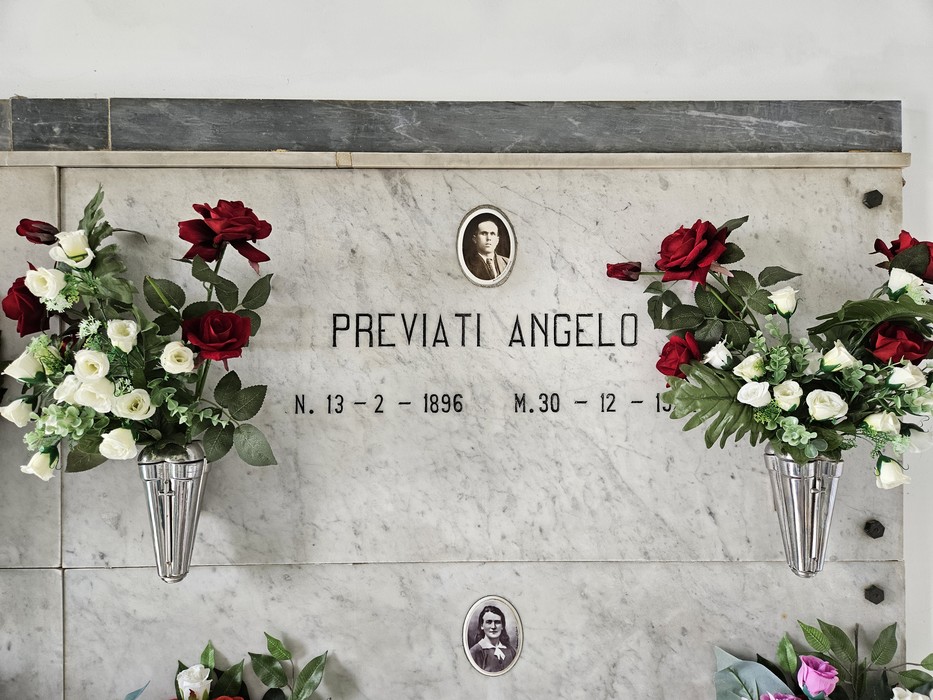 Monumento commemorativo con fiori artificiali e fotografie, dedicato ai caduti, rappresenta un tributo di memoria.