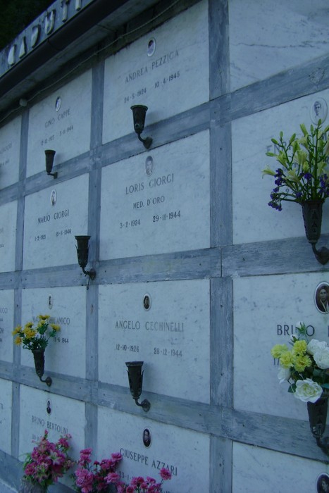 Sepolcri commemorativi dei caduti per la libertà, con nomi e fiori in ricordo dei sacrifici.