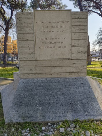 Monumento ai caduti militari, dedicato ai soldati e ai partigiani. Situato in un'area verde, con alberi circostanti.
