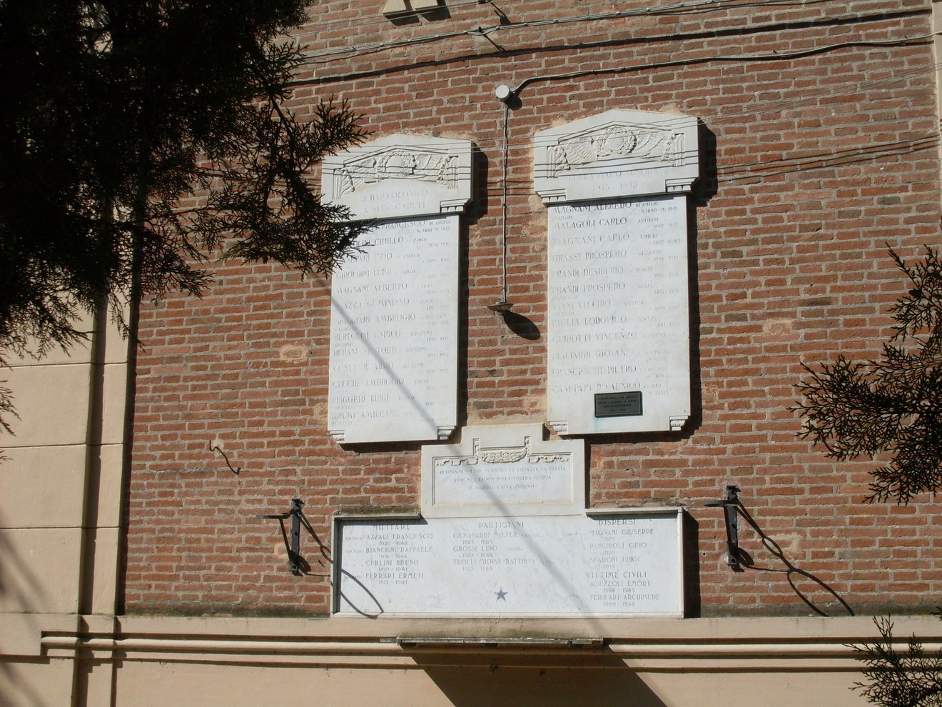 Lapide commemorativa ai caduti, situata a San Bartolomeo, con nomi incisi su marmo bianco.