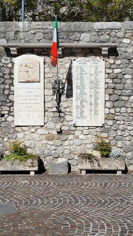Lapide commemorativa dedicata ai caduti della guerra 1940-1945 con bandiera italiana e listino nomi su pietra.