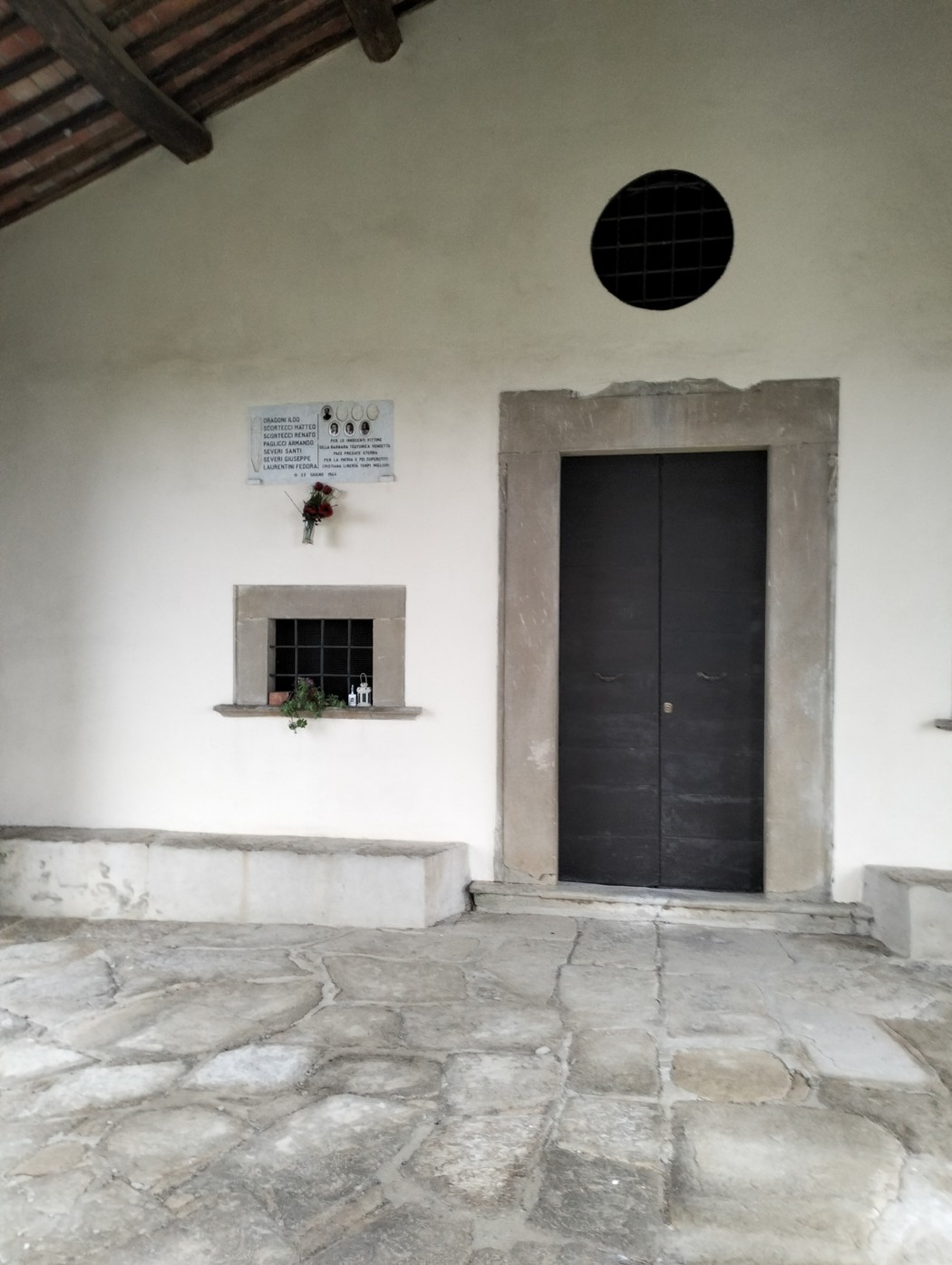 Lapide commemorativa dedicata ai caduti di Valloni, situata in un edificio con porta e finestre.