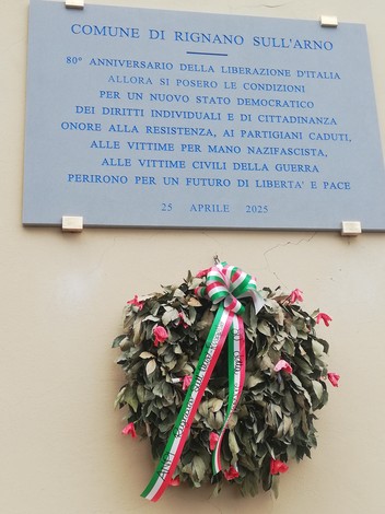 Lapide commemorativa del 80° anniversario della liberazione d'Italia, con una corona di fiori.