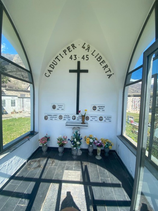 Interno della cappella dedicata ai caduti per la libertà, con croce e fiori in un ambiente sereno e commemorativo.