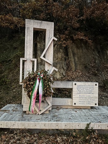 Monumento alla battaglia di Bosco Martese con corona di fiori e iscrizioni commemorative sul retro.