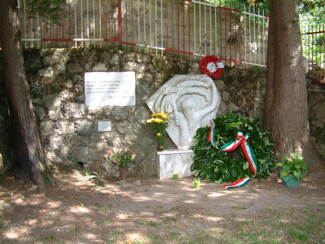 Monumento di Mandrione, commemorazione di eventi storici con elementi floreali e decorazioni tricolori.