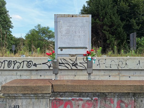 Lapide commemorativa dedicata a Lavezzaro, Novelli e Zanotti, adornata con fiori e tricolore.