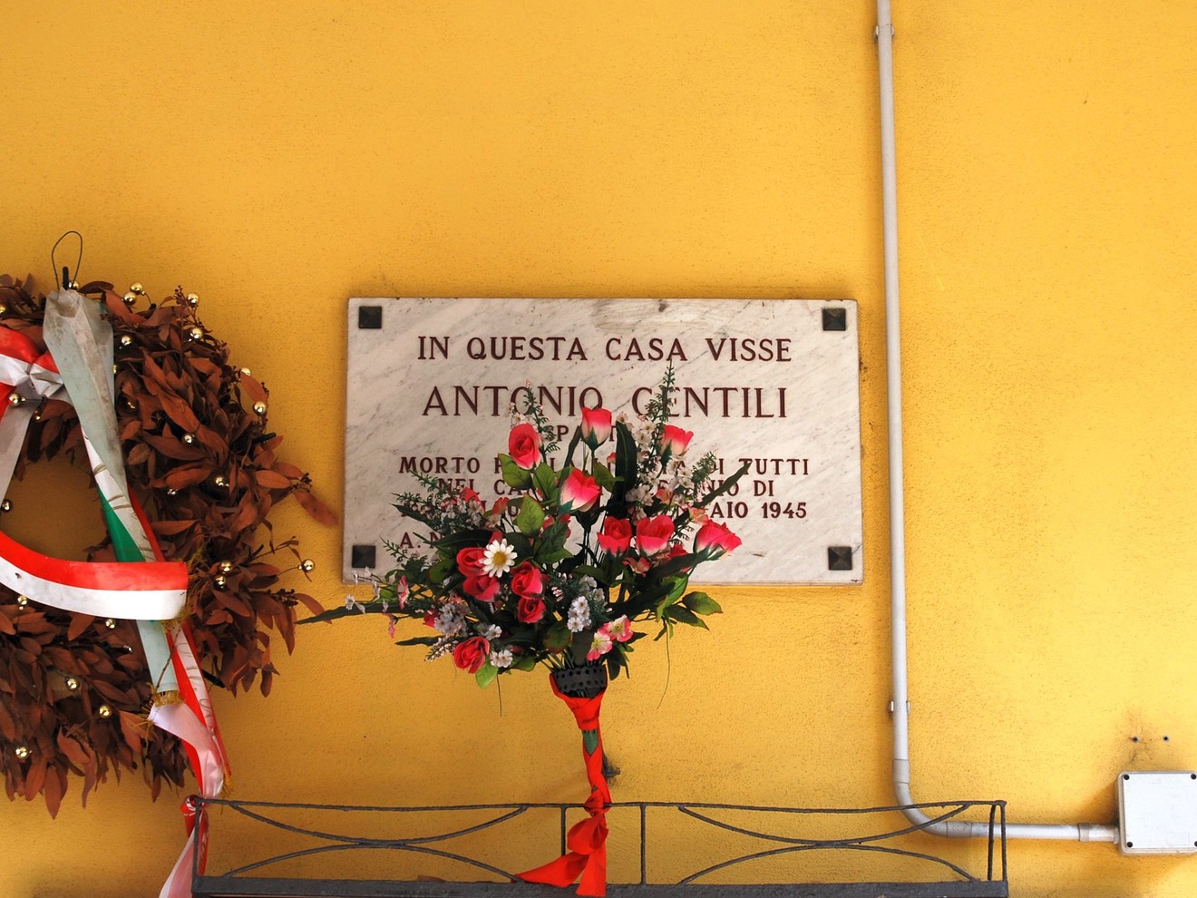 Lapide commemorativa dedicata ad Antonio Gentili, situata su un muro giallo.