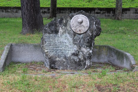 Monumento in pietra dedicato ai martiri della Resistenza, con medaglia commemorativa e iscrizioni.