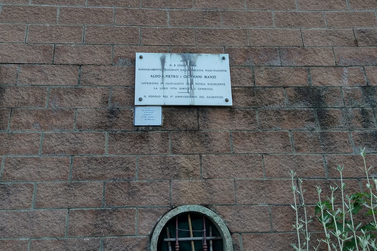 Lapide commemorativa dedicata ai fratelli Manzi, su una parete in pietra.