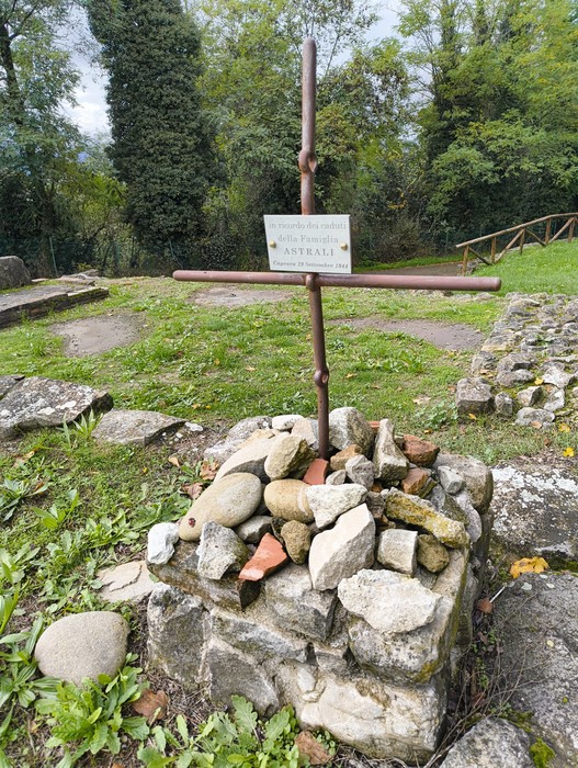 Rovine di Caprara di Sopra, con croce commemorativa e resti murari immersi nella natura.