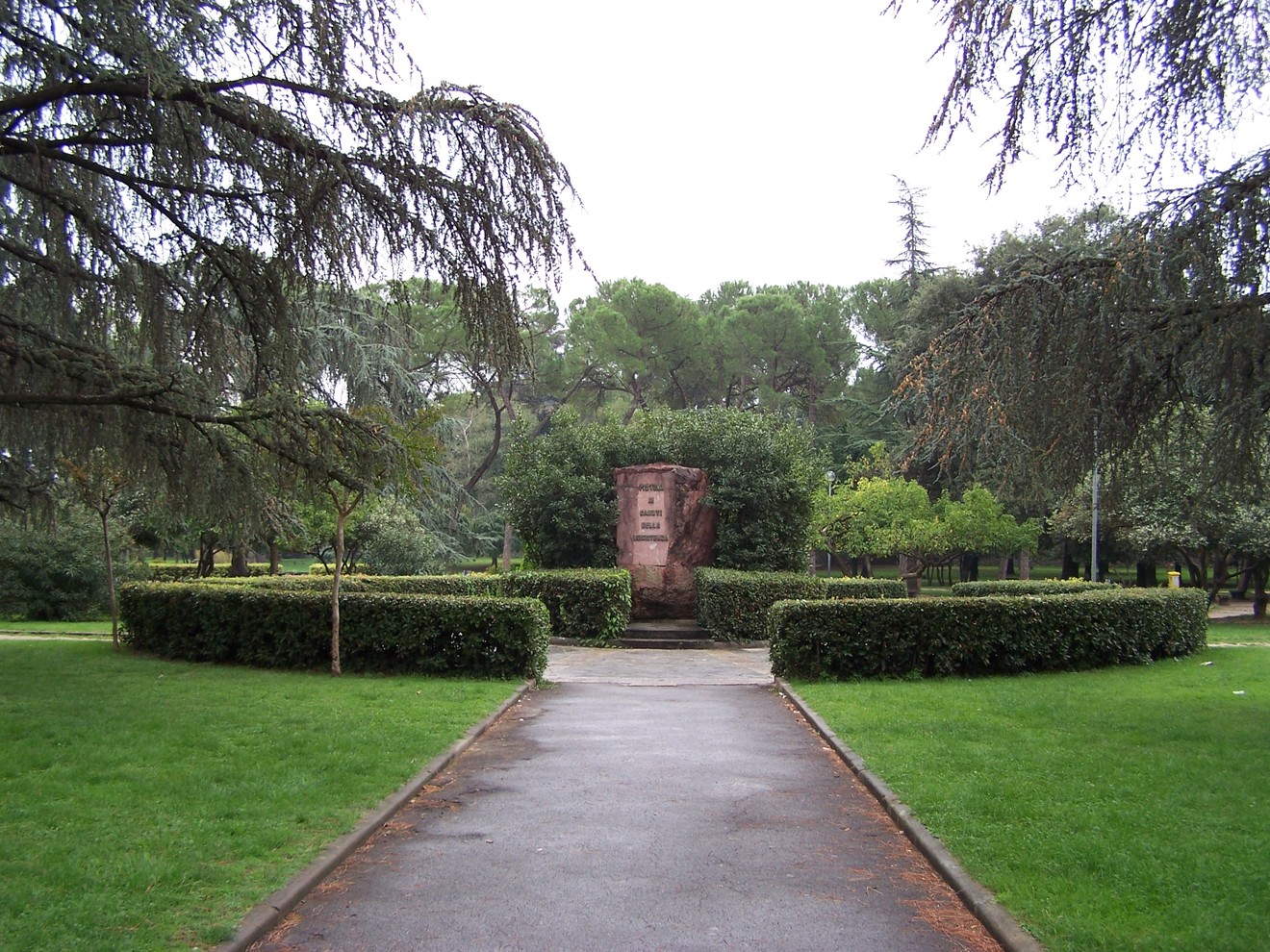 Monumento ai Caduti della Resistenza, circondato da un verdeggiante parco e alberi, in un'atmosfera di commemorazione.