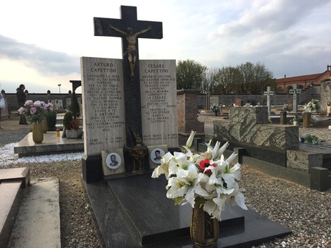Sepolcro dei Capettini con croce, lapidi commemorative e fiori freschi su un cimitero tranquillo.