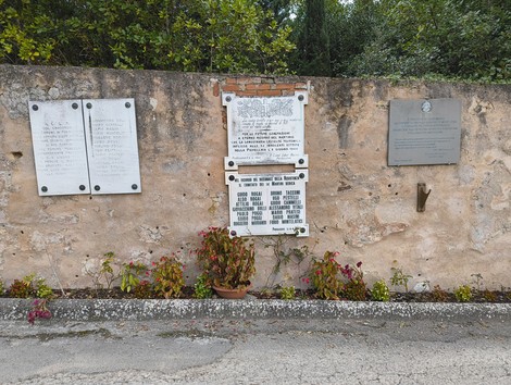 Lapide di Pievecchia, memoriale storico con iscrizioni su parete rocciosa, circondata da vegetazione.