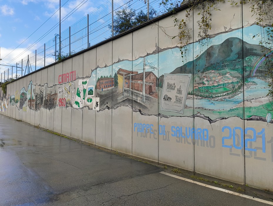 Murale di Pioppe: arte urbana che celebra la storia e la comunità locale con colori vivaci e dettagli narrativi.