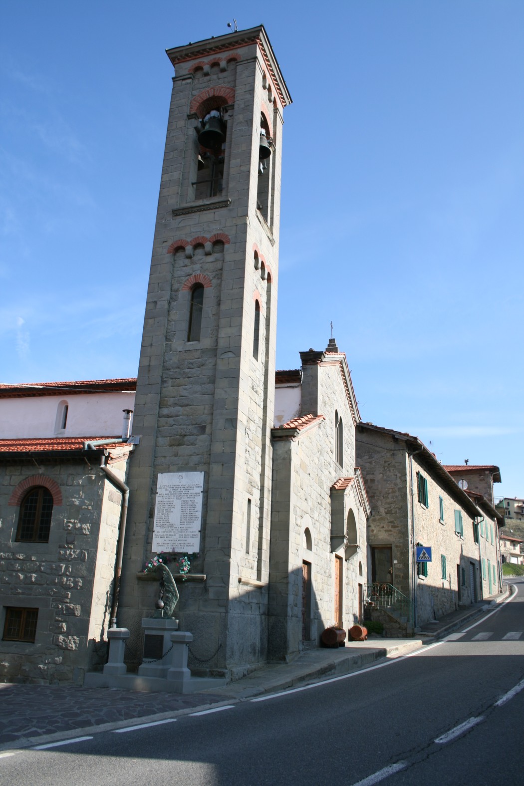 Lapide della chiesa della Consuma, con campanile e facciata in pietra, situata lungo la strada.