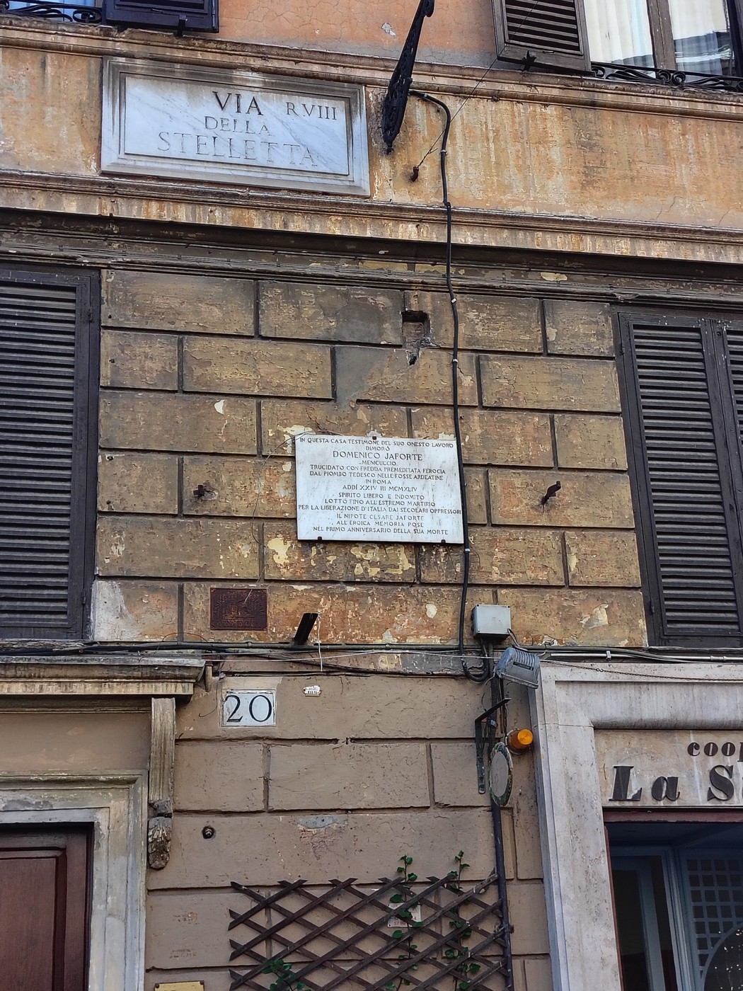 Lapide commemorativa su un edificio antico, in via della Stelletta, che ricorda un evento storico locale.