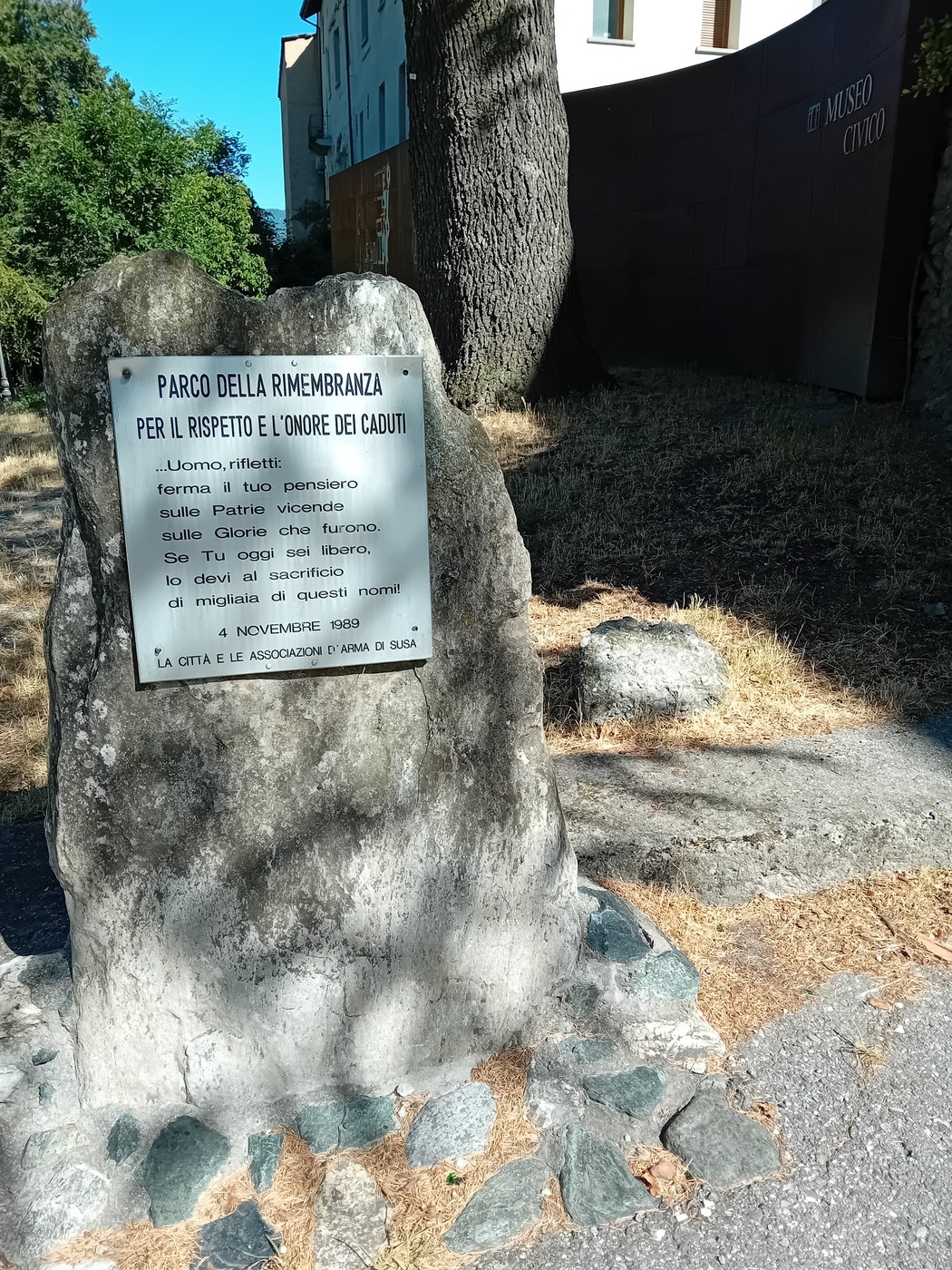 Parco della Rimembranza con una targa dedicata al rispetto e all'onore dei caduti in un contesto naturale.
