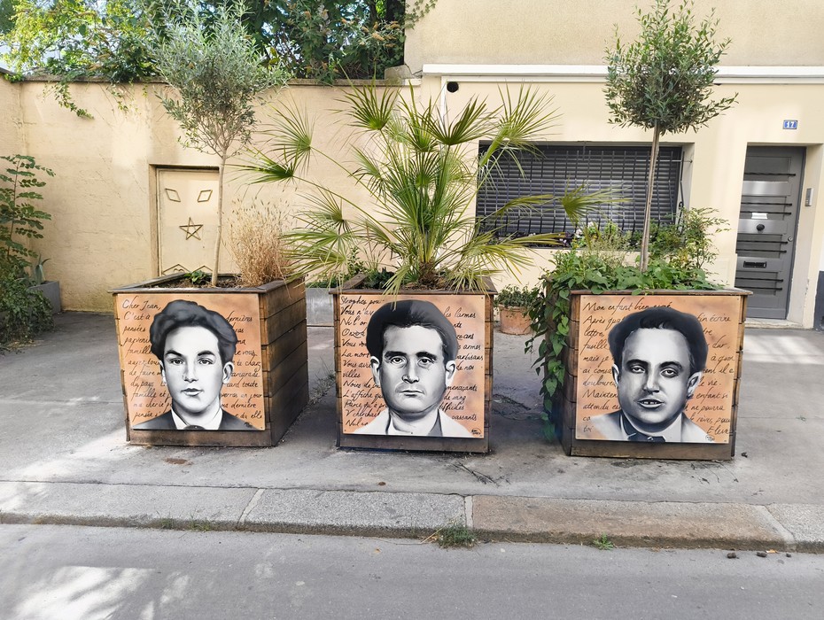 Immagine di tre cassonetti decorati con ritratti e scritte commemorative del Gruppo Manouchian.