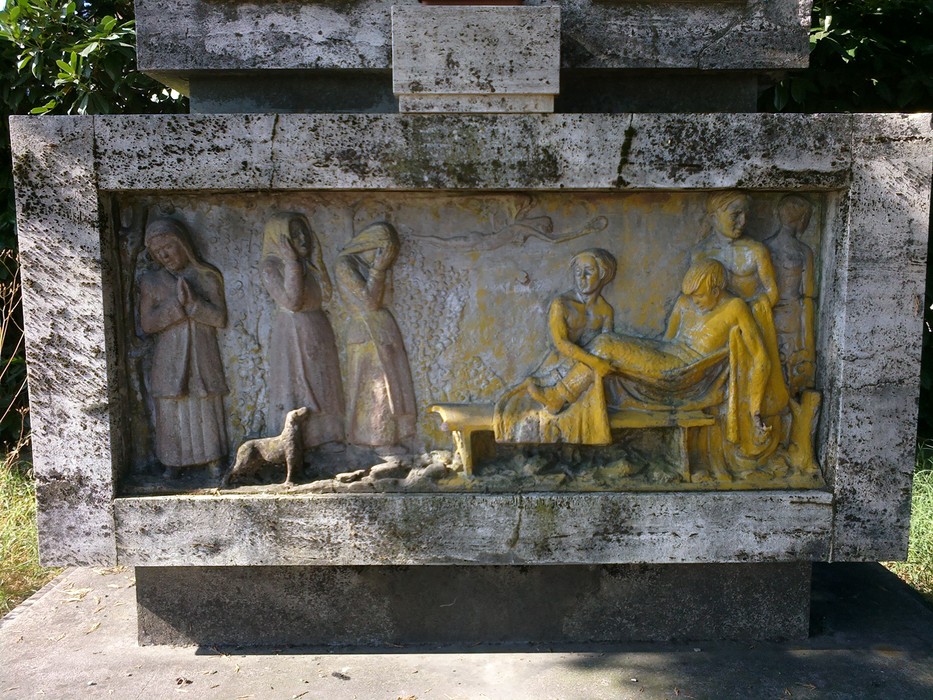 Monumento commemorativo con bassorilievi dedicati ai caduti, immerso nella natura di Villa Gaida.