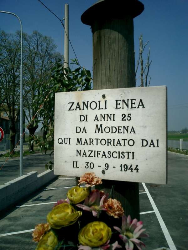 Targa commemorativa dedicata a Enea Zanoli, vittima del nazifascismo a Modena nel 1944, con fiori.