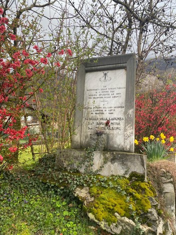 Monumento dedicato a Della Valle, circondato da fiori e vegetazione, simbolo di ricordo e storia locali.