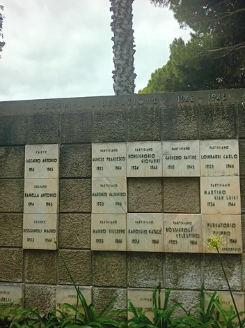 Monumento ai caduti con iscrizioni commemorative e decorazioni floreali, simbolo di memoria storica.