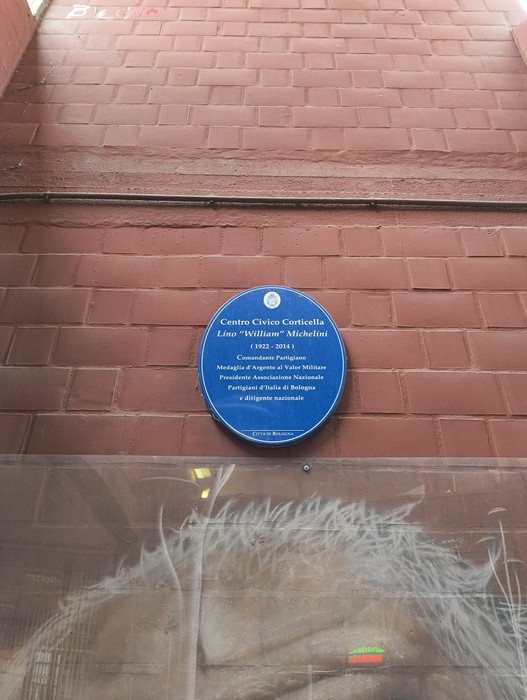 Murale dedicato a Lisa "Willa" Michelini, con targa commemorativa su muro rosso.