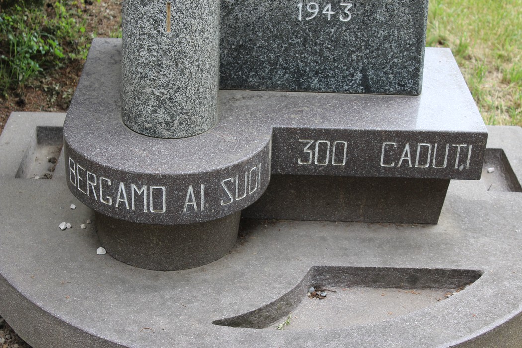 Monumento alla Divisione Acqui, commemorativo con iscrizioni e decorazioni, immerso nel verde.