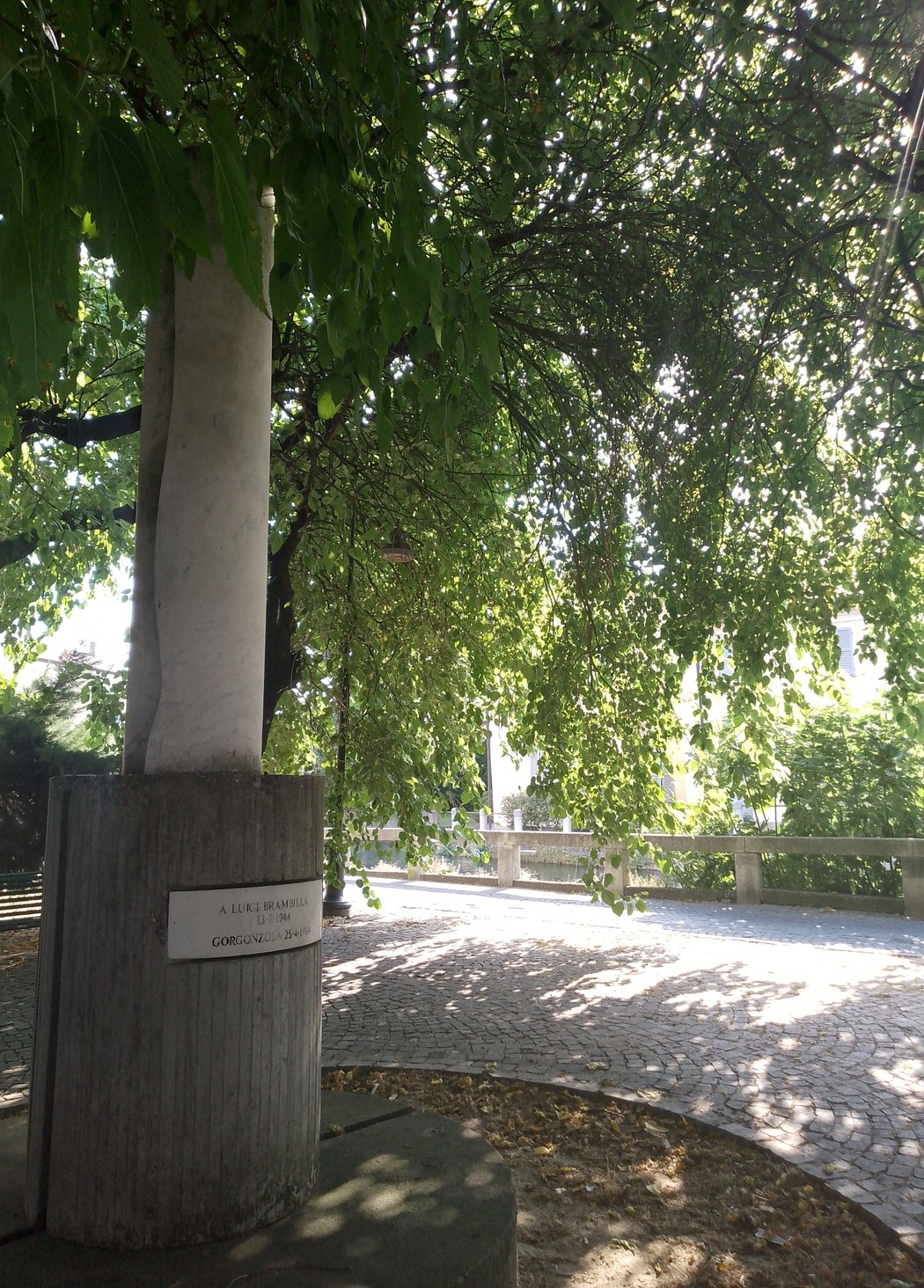 Monumento a Brambilla, immerso nel verde, con un'architettura semplice e armoniosa circondata da alberi.