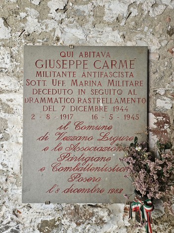 Lapide commemorativa dedicata a Giuseppe Carmé, militante antifascista, situata su un muro di pietra.